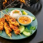 Brochettes de volaille marinées curry-coco grillées au brasero plancha, servies sur une assiette