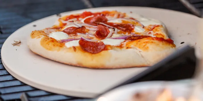 Pizza sur une pierre de cuisson réfractaire destinée au barbecue