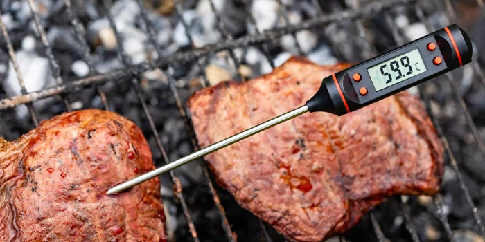 Sonde de cuisson (thermomètre à viande) insérée dans une pièce de viande sur un barbecue